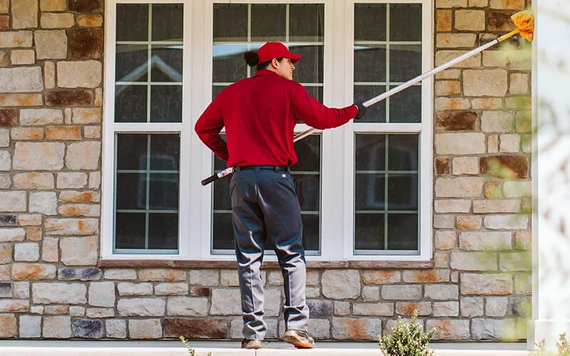 Pest Technician Sweeping Exterior of home