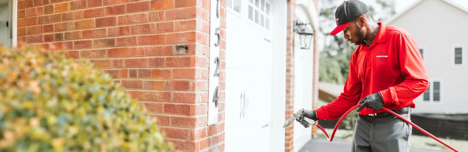 tech spraying exterior of brick home, residential pest control